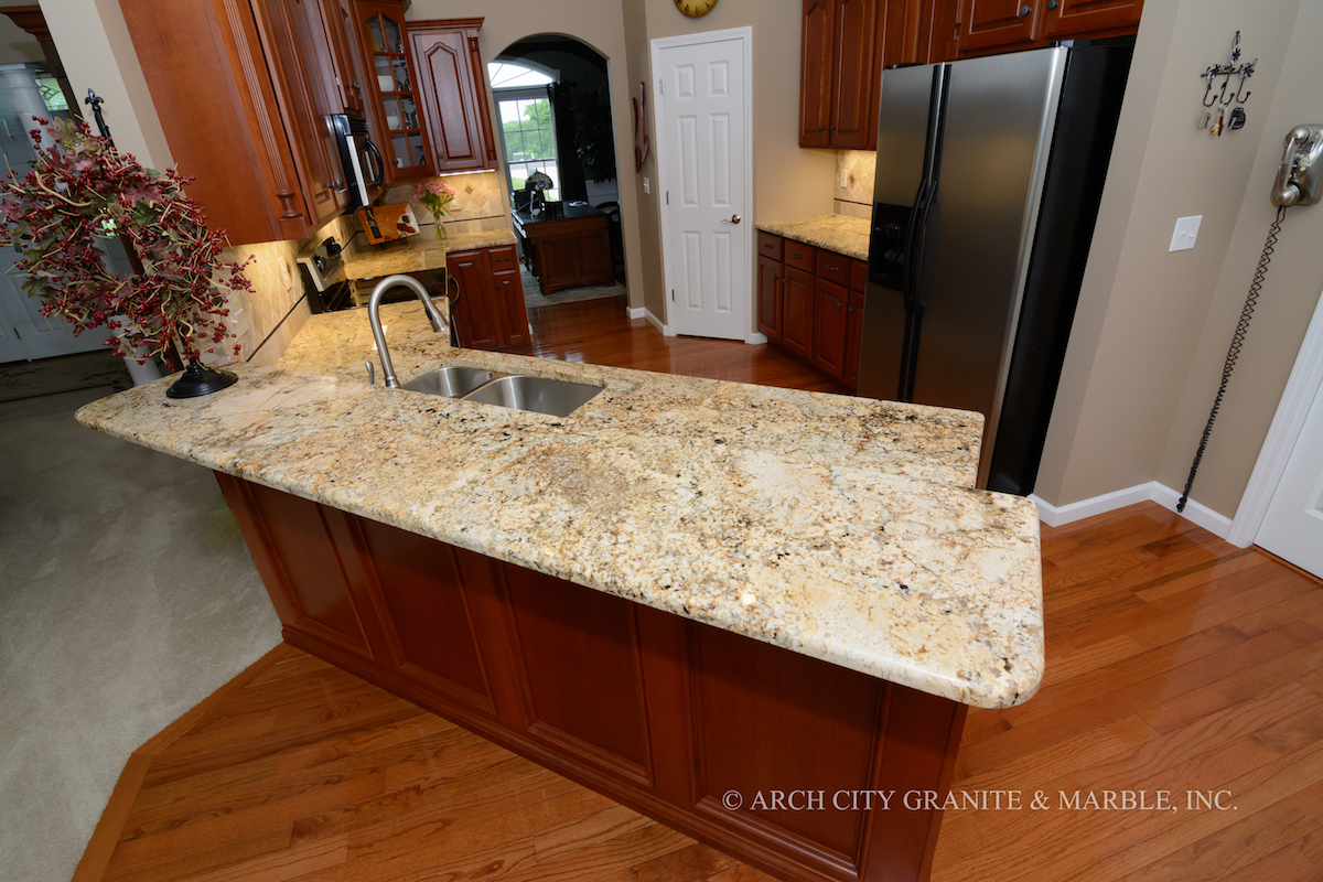 Solarius granite with primary Gold color in it is paired with dark wood colored kitchen cabinets in st louis area